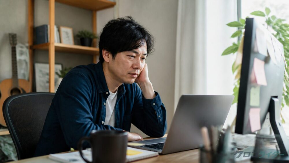 ホームオフィスで複数のタスクに追われるWebライターの男性
